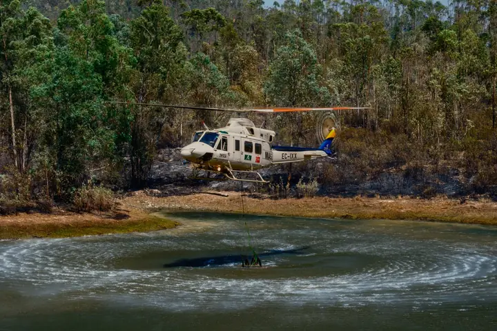 Helicóptero cargando agua en un embalse con ondas circulares