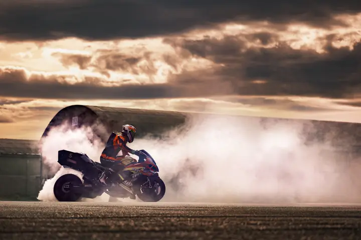 Burnout con una moto rodeada de humo bajo un cielo dramático