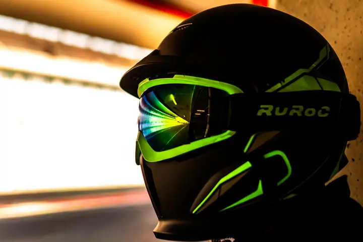 Casco negro con visor reflectante y detalles verdes en el box