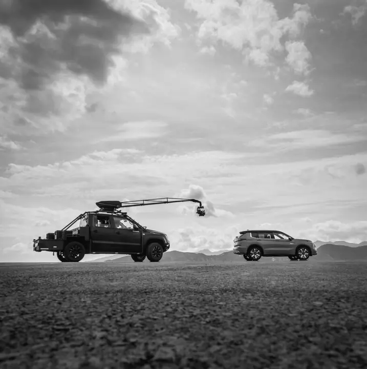 Pickup con grúa de cámara junto a un SUV, en blanco y negro