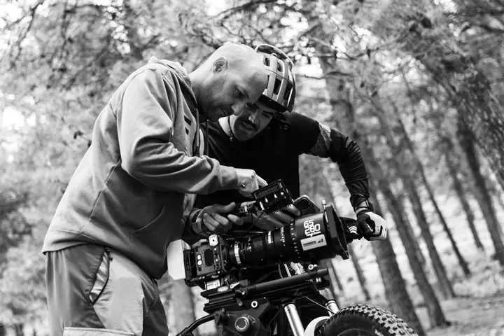 Operador revisando una cámara de cine con zoom en un bosque, en blanco y negro