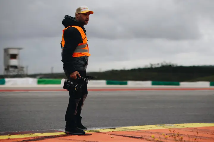 Operador con cámara de cine en mano junto a la curva de un circuito