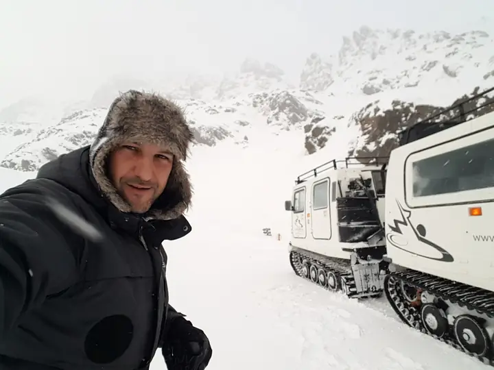 Selfie en la nieve junto a un vehículo oruga de montaña